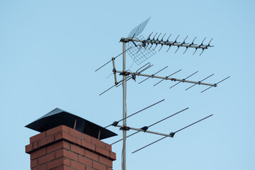TV antenna on red roof. television antenna on roof with blue sky. Brick pipe house and media...