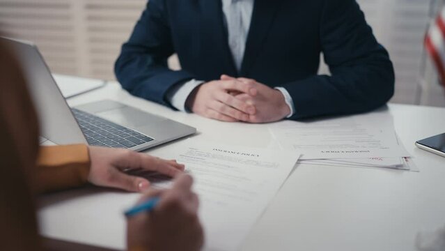 Client signing insurance policy document with agent, insuring health or property