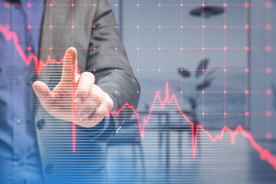 Close up of businessman hand pointing at falling red business graph grid on blurry office interior background. Crisis, recession and stock market concept. Double exposure.