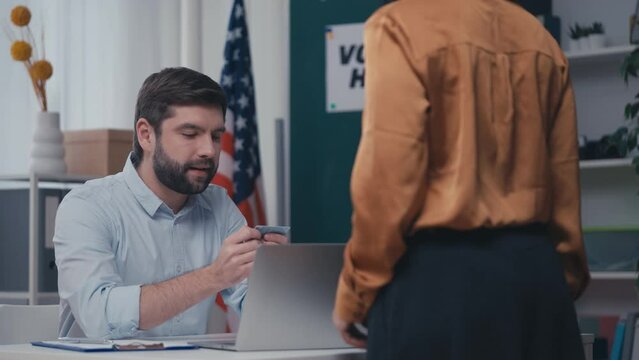 US polling station employee processing voters on election day, checking ID