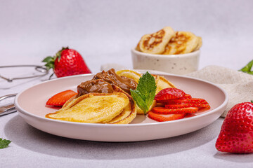 Cottage cheese pancakes, syrniki, curd fritters with strawberry, mint and powdered sugar on plate