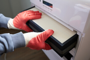 A man wearing gloves is changing the air filter.