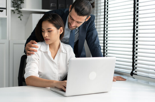 Sexual harassment at workplace concept. Attractive Asia woman being molested by caucasian businessman  at office