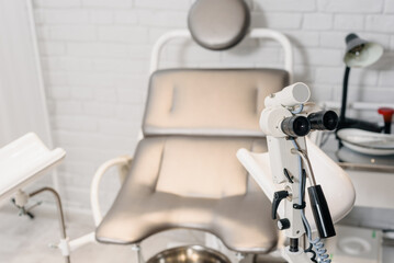 Gynecological chair and colposcopy equipment in modern clinic, closeup photo
