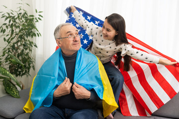 Fototapeta na wymiar grandfather and granddaughter with the flags of the USA and Ukraine