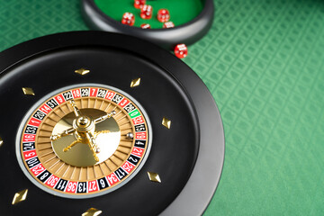 Casino. Gambling games theme.  Roulette wheel, dice and poker chips on the casino felt green table.