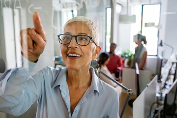 Mature female coach making notes of information during workflow planning strategy for project