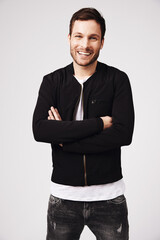 Portrait, happy man and arms crossed in white background, casual style and confident attitude. Handsome young male model, laughing guy and smile in studio for good mood, happiness and fashion clothes