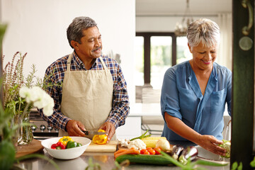 Food, elderly couple and cooking while happy in kitchen of their home. Teamwork or help, vegetables and senior married people preparing a meal for dinner or lunch together in their house.
