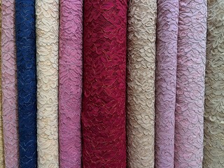 Colorful pile of tulle fabric with floral design for bridal wedding dress at fabric shop.