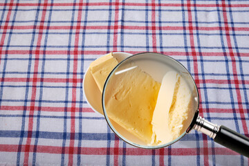 Collage: butter in a bowl through a magnifying glass on the background of a checkered tablecloth