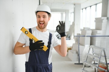 Portrait of positive, handsome young male builder in hard hat.