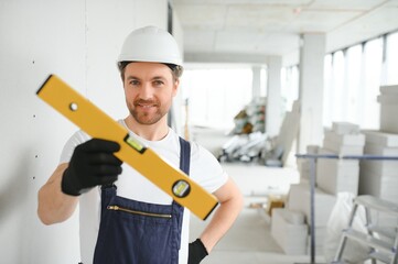 Portrait of positive, handsome young male builder in hard hat.