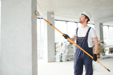 Worker renewing apartment on wall background.