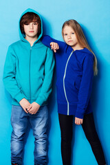Fashion, portrait and young girl and boy in a studio with a casual, cool and stylish outfit. Youth, friendship and portrait of teenager models posing together with trendy style by a blue background.