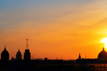 Fototapeta na wymiar Panoramic view of the roofs, towers, domes of churches and cathedrals silhouetted against sunset light on spring evening. Saint-Petersburg, Russia. Travelling and tourism concept. Copy space.
