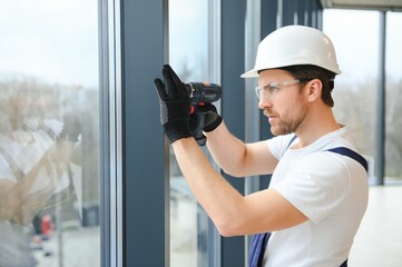 handsome young man installing bay window in new house construction site.