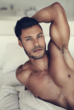Portrait, body and wake up with a sexy man lying shirtless in the bedroom of his home in the morning. Relax, arm and muscle with a handsome young male model resting topless in bed for sensuality