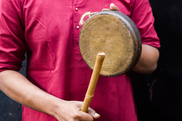 Fototapeta na wymiar Kasar or gong bell being performed or hit with wooden stick by Indian male in traditional attire during hindu puja rituals. Kasar is a musical instrument which is made of brass.