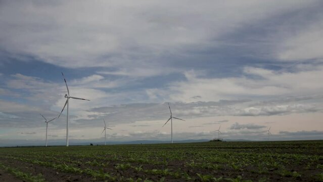 Windmills in the field against time lapse clouds .camera is moving from left to rigth