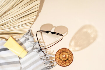 Sunglasses, cream, linen towel, wine and cocktail glass, palm leaf summer beach holiday concept.