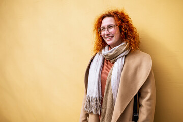 Natural portrait of smiling caucasian ginger woman with freckles and curly hair.
