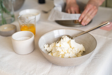 Сottage cheese in a bowl. Ingredients for making cheesecake on the table