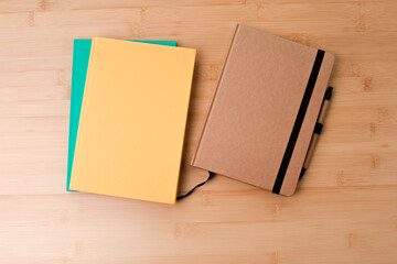 Template with stationery. Green, brown and yellow notebooks on a wooden, bamboo background. Flat lay. Copy space