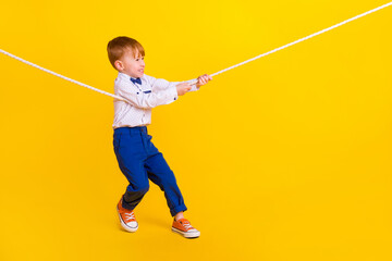 Profile side full length photo of small boy playing tug war game losing heavy challenge isolated vibrant color background