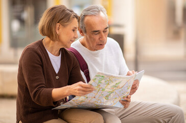 Mature Couple Looking At Map Choosing Destination For Vacation Outside
