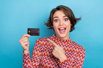 Photo of excited funky lady wear pink shirt pointing finger bank card isolated blue color background