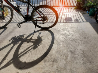 sun light pass steel fence make  mountain bike shadow on cement floor , abstract backgroud