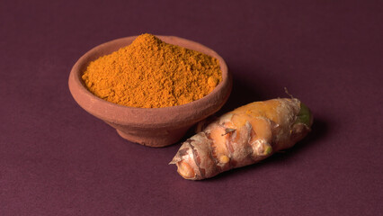 Turmeric powder in wooden bowl and fresh turmeric root on textured background. Herbs are native ,Food and drink, diet nutrition, health care concept.