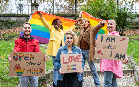 Group of young activist for lgbt rights with rainbow flag and banner, diverse people of gay and lesbian community, gay Pride Parade