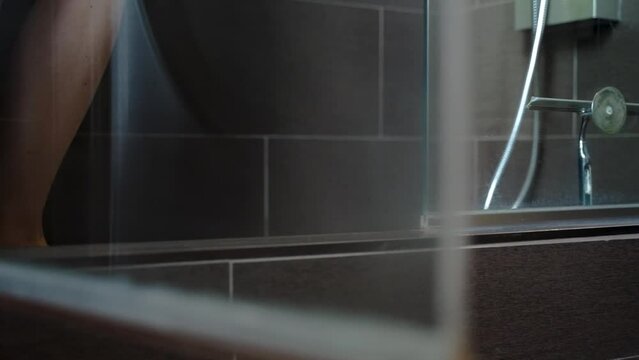 Woman stepping into a bathroom shower.