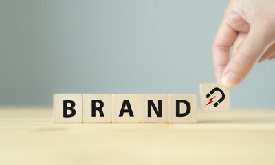 Build brand loyalty concept. Customers continue engaging and purchasing from the same brand, positive feelings toward brand. Wooden cube blocks with BRAND text and magnet icon on clean background.