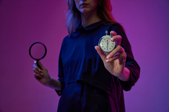 Time management and research. Young woman holding clock and magnifying glass over gradient purple background in neon light. Concept of business, modern technologies, innovations - Powered by Adobe