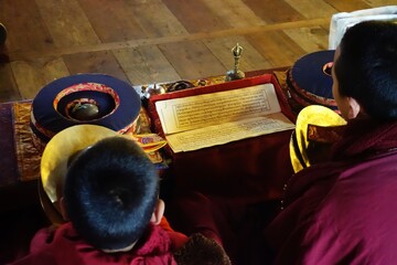 Two young lamas of Hinang Monastery in the Nepalese Himalayas, reading a religious scripture...