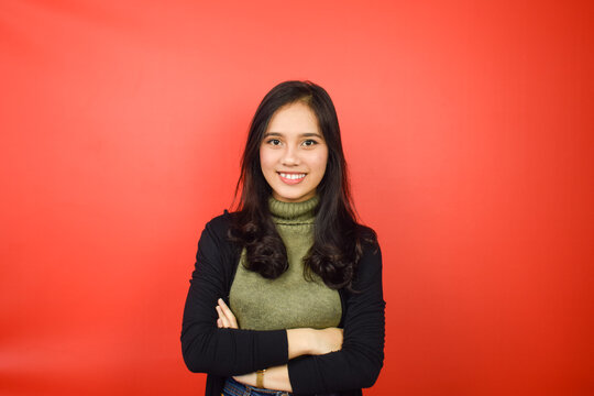 Folding arms Smiling and Looking at Camera Of Beautiful Asian Woman Isolated On Red Background