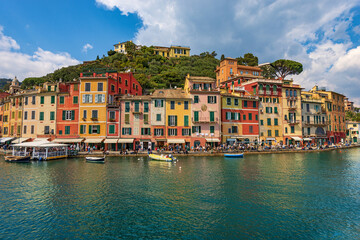 Multi coloured houses and port of Portofino, luxury tourist resort in Genoa Province, Liguria, Italy, Europe. Waterfront and promenade with many tourists on a sunny spring day. Mediterranean sea. - obrazy, fototapety, plakaty