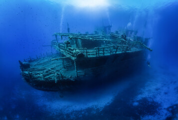 A group of unrecognizable divers explore a sunken shipwreck in the blue, mediterranean sea at Naxos...