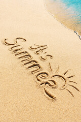 It is Summer written text on sunny beach with sea wave. Travel and holidays seasonal concept photo.