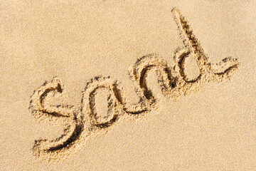 Sand word written close-up on sunny summer beach background