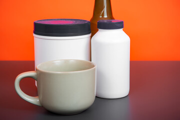 White plastic jars of sports nutrition on an orange background.
