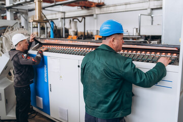 An engineer and a technician working on the production of PVC pipes.