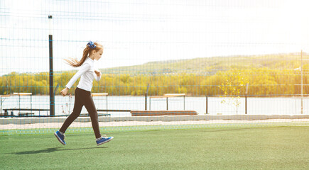 Caucasian little girl is running in the stadium, concept of outdoor activity, sport, exercise and competition learning for kid development.