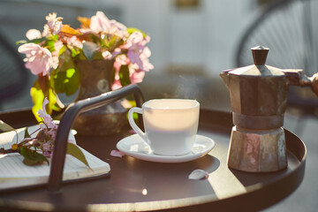 Cup of coffee flowers and notebook on the small black table