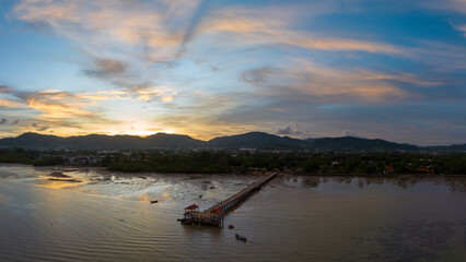 Obraz premium aerial photography cloud above Palai pier at beautiful sunset..Palai pier is next to Chalong pier..fishing boats parking on the beach..colorful cloud above the mountain range background..