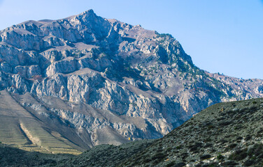 Mountain view on a clear autumn day. A gorge in Ingushetia. Jeyrakh district in Ingushetia. Rocks and trees in a mountainous area. Hiking in the mountains. Colorful mountains and blue sky.