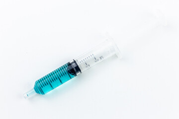 Medical syringe with blue liquid inside on white background with copy space for your text.